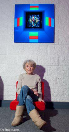 Dorothy Tanner sitting in chair below Lumonics light sculpture