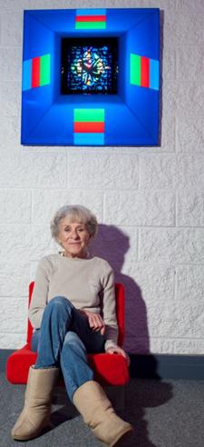 Dorothy Tanner sitting in a chair under Lumonics light sculpture